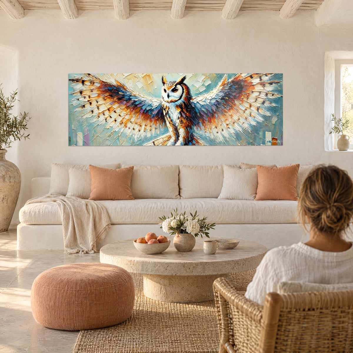 Tableau hibou aux ailes déployées bleu et ocre, plumes blanches en empâtements, au-dessus d'un canapé dans un salon lumineux