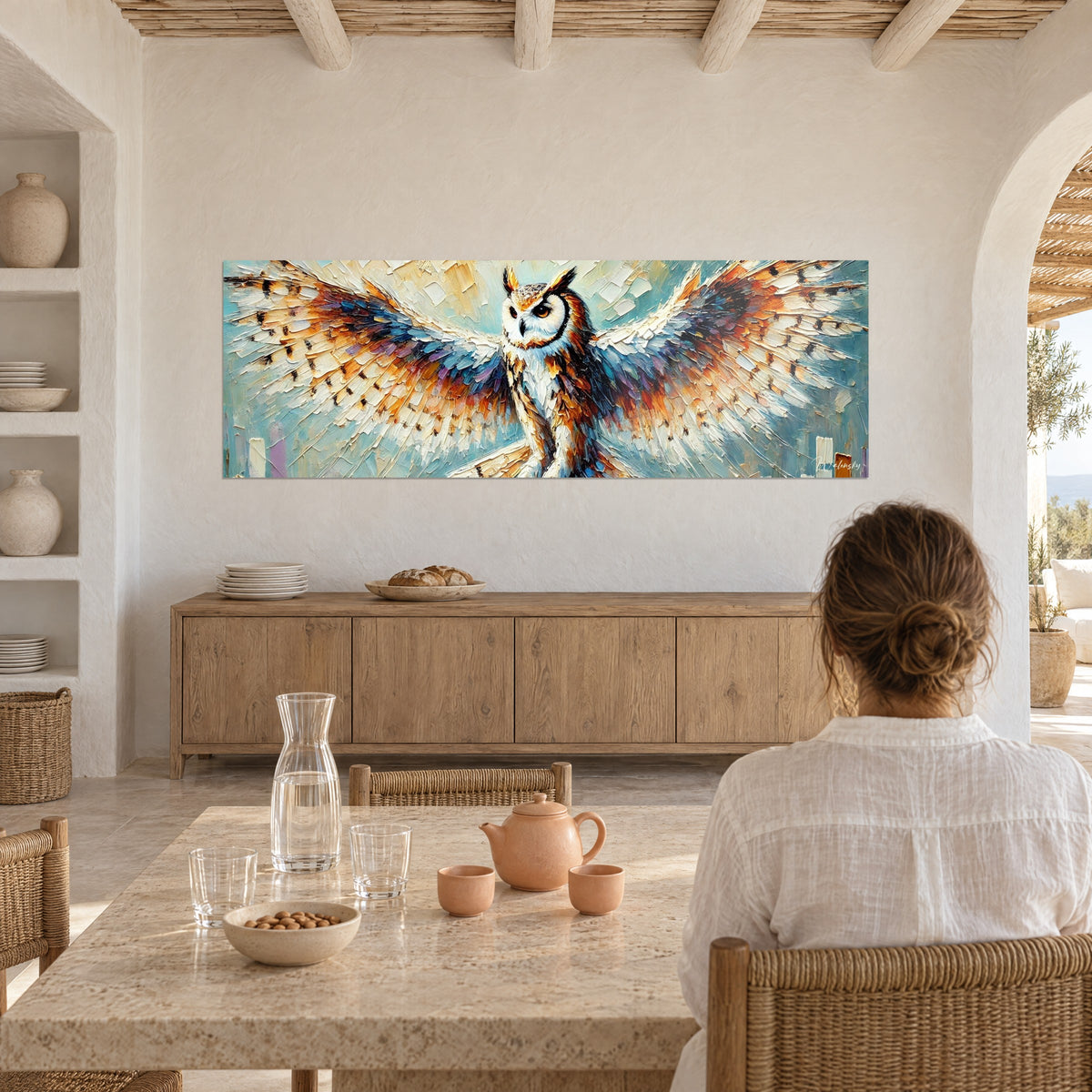 Tableau strigidé aux plumes en relief ivoire et bleu, yeux ambrés, sur un mur blanc audessus d'un buffet en bois clair