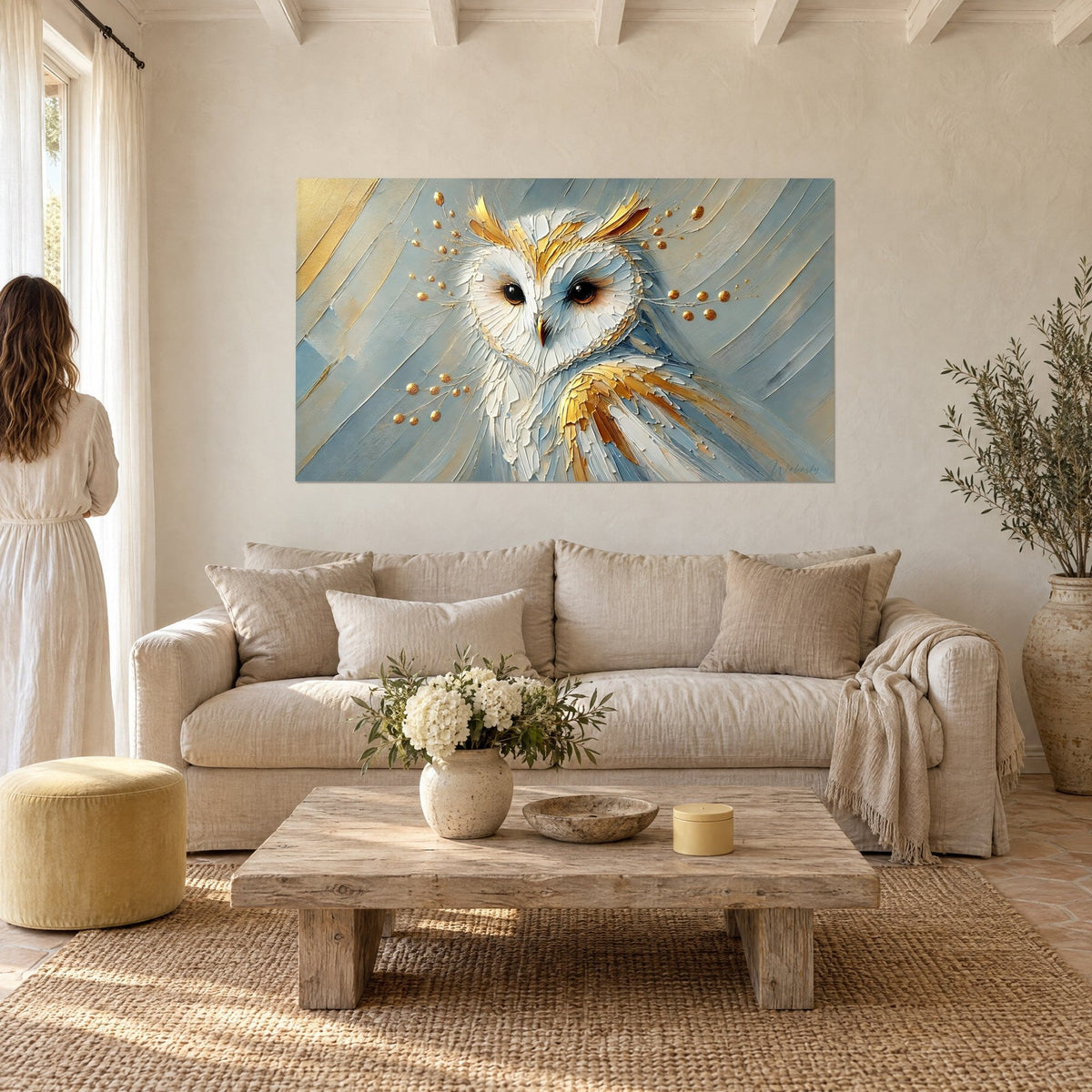 Gemälde Schleiereule mit herzförmigem Gesicht, goldene und blaugraue Federn, Goldtropfen, Frau von hinten, über einem Sofa in einem hellen Wohnzimmer