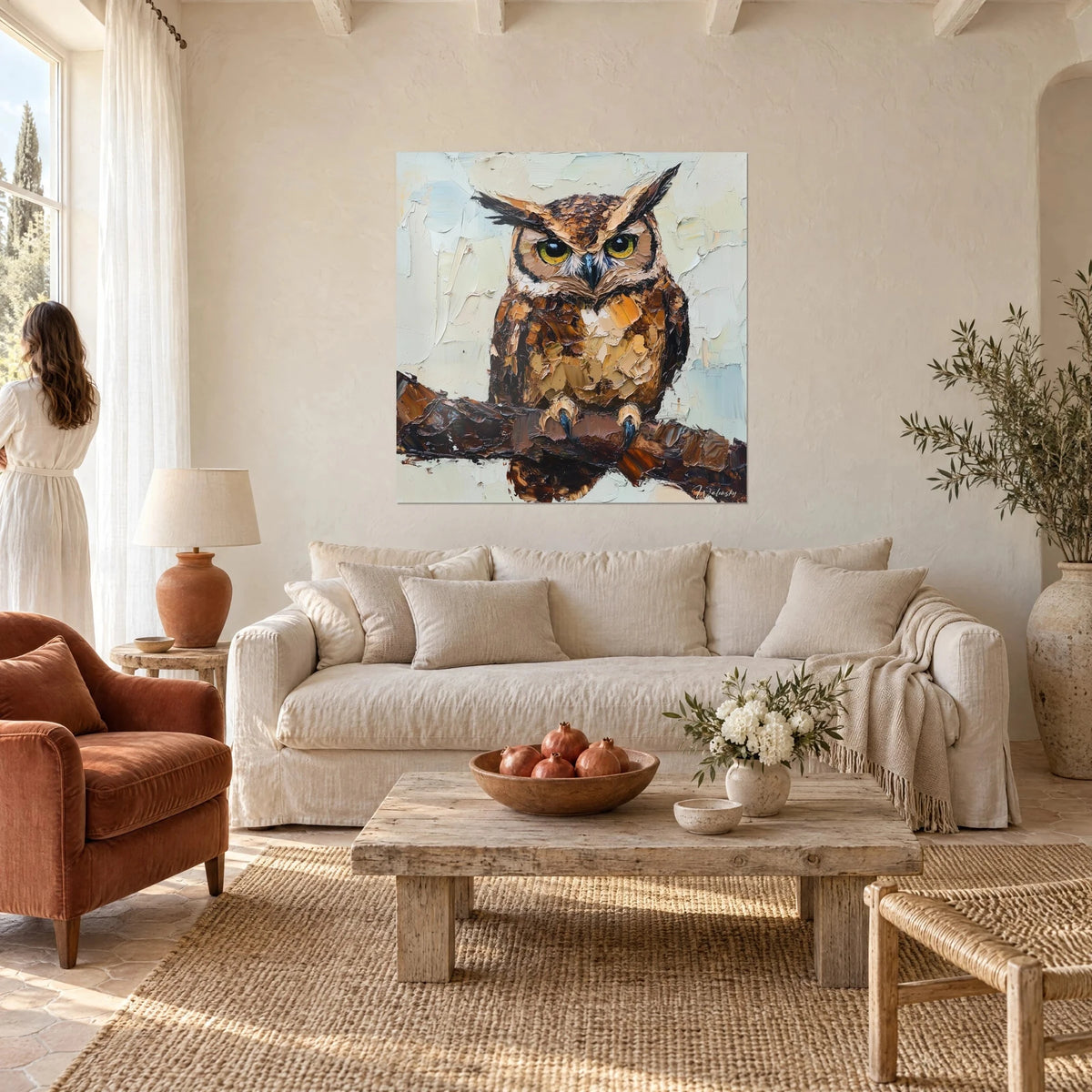 Tableau hibou aux yeux jaunes perché sur une branche brune, empâtements ocre et bleu pâle, au-dessus d'un canapé dans un salon lumineux