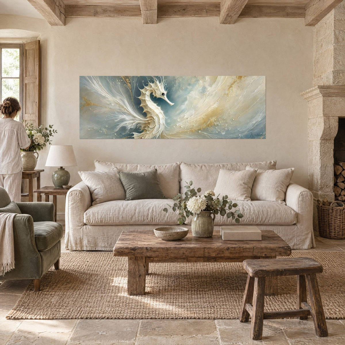 Wall art ivory seahorse with feathered fins, grey-blue background and gold dust, a woman seen from behind above a sofa in a bright living room