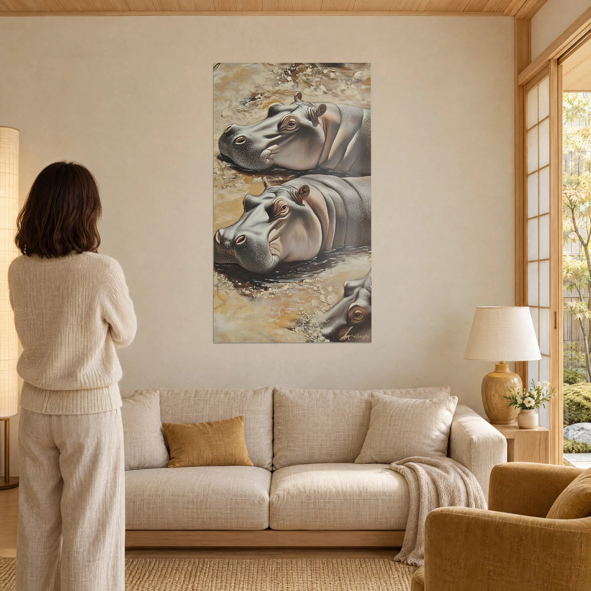 Cuadro de hipopótamos adormilados con reflejos gris perla y ocre dorado, piel granulosa, mujer de espaldas, encima de un sofá en un salón luminoso
