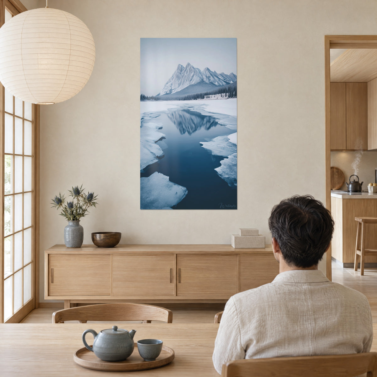 Tableau paysage hivernal aux blocs de glace blanche et eau bleu pétrole, homme de dos assis à table, séjour japandi lumineux