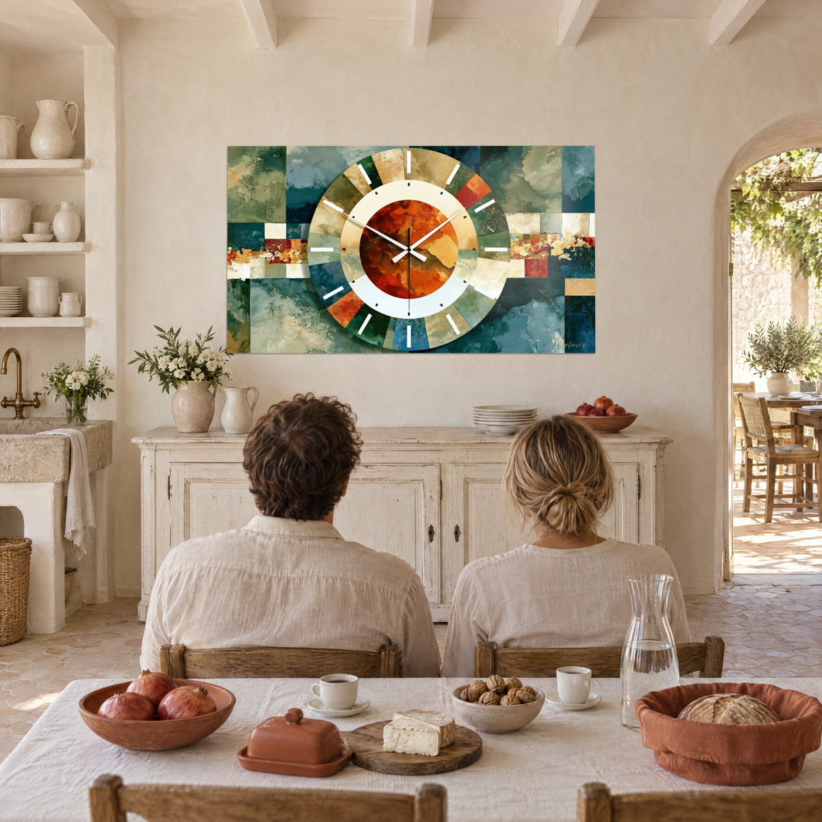 Tableau horloge géométrique aux touches bleu pétrole et terracotta, accrochée dans un mas provençal, couple de dos attablé devant
