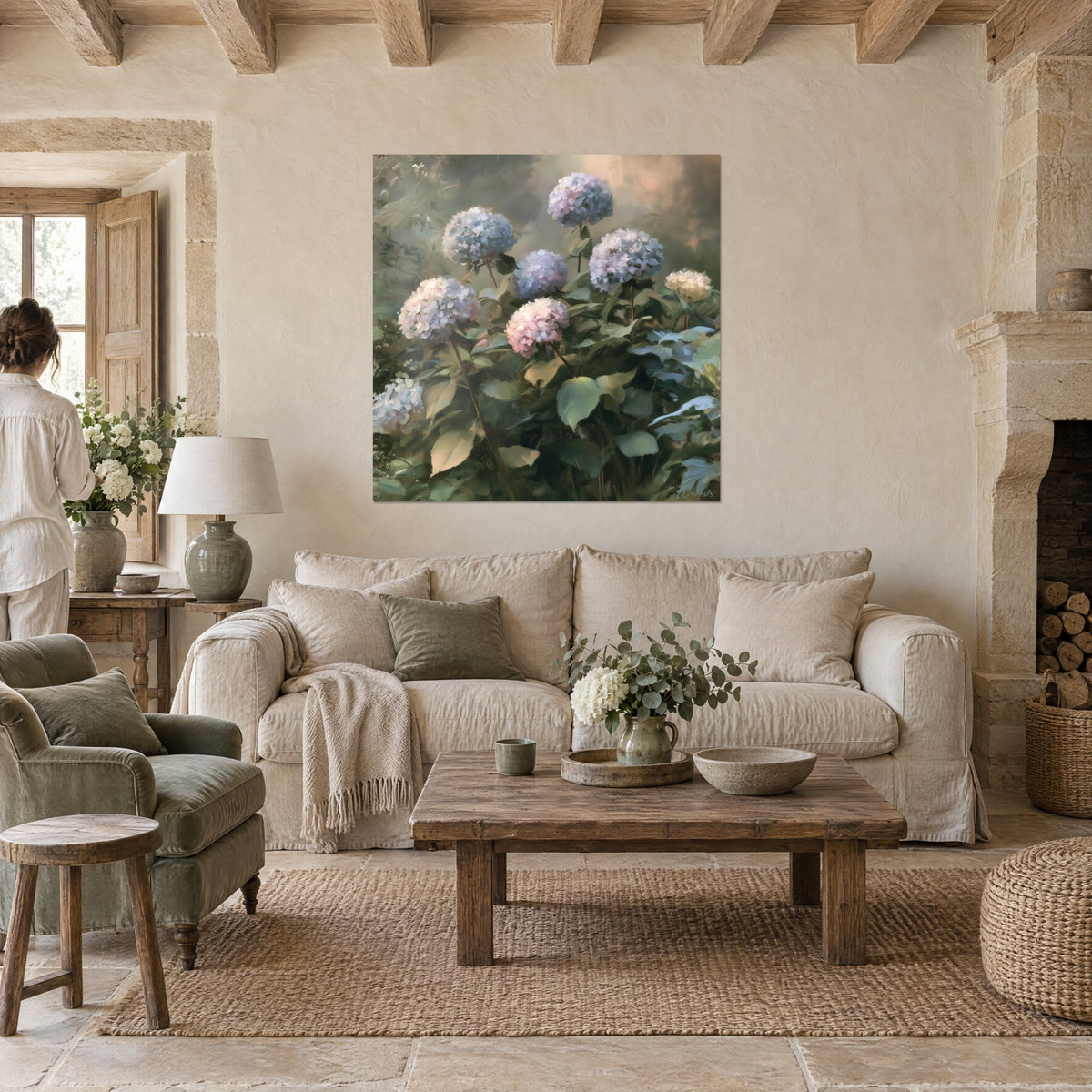Cuadro de hortensias azules y rosa pastel con grandes umbelas, follaje verde salvia, encima de un sofá en un salón luminoso