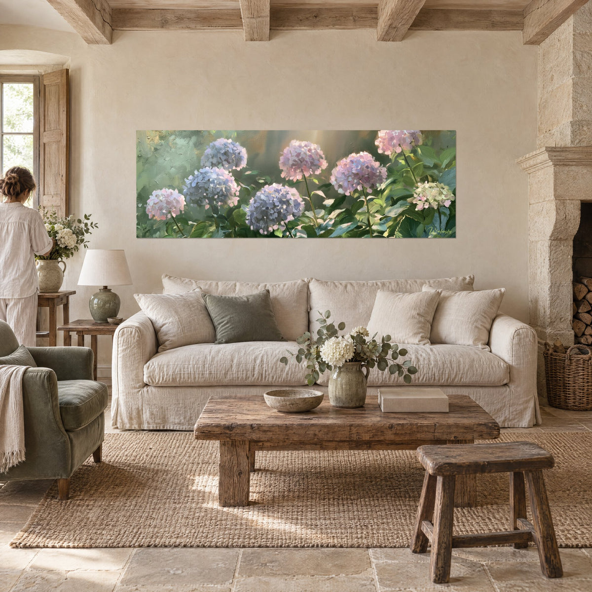 Schilderij met blauwe en roze hortensia's in volle bloei, saliegroen blad en gouden licht, boven een bank in een lichte woonkamer