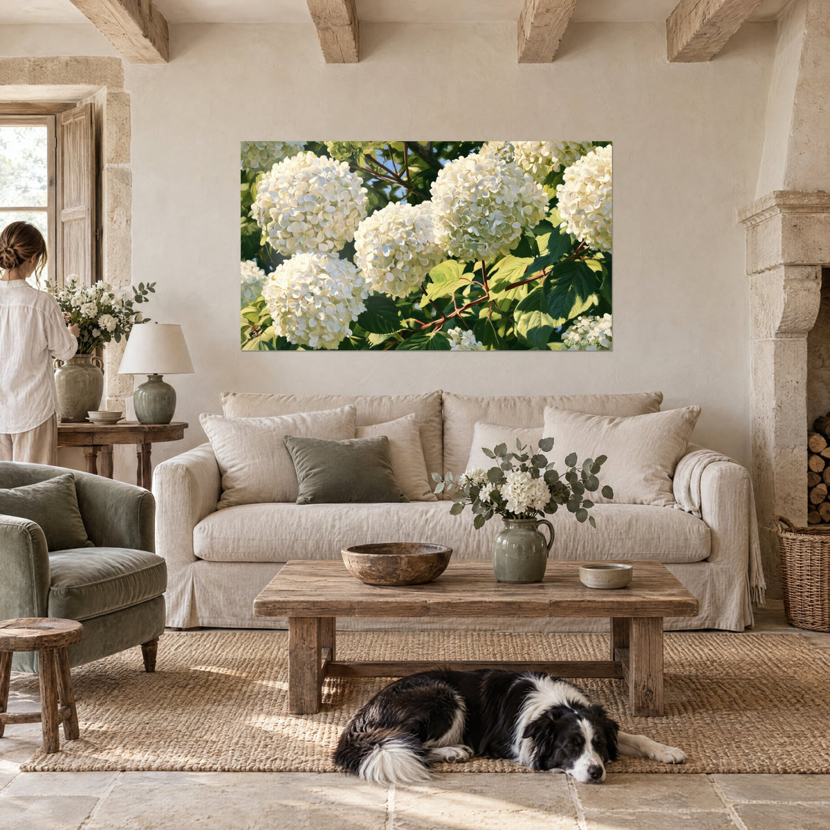 Wall art white hydrangeas in big round clusters, soft green leaves and brown branches in the light, above a sofa in a bright living room