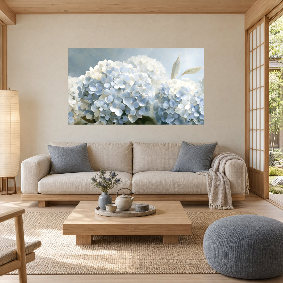 Quadro ortensie in grandi ombrelle azzurro pallido e bianco crema, foglie appuntite, sopra un divano in un soggiorno luminoso