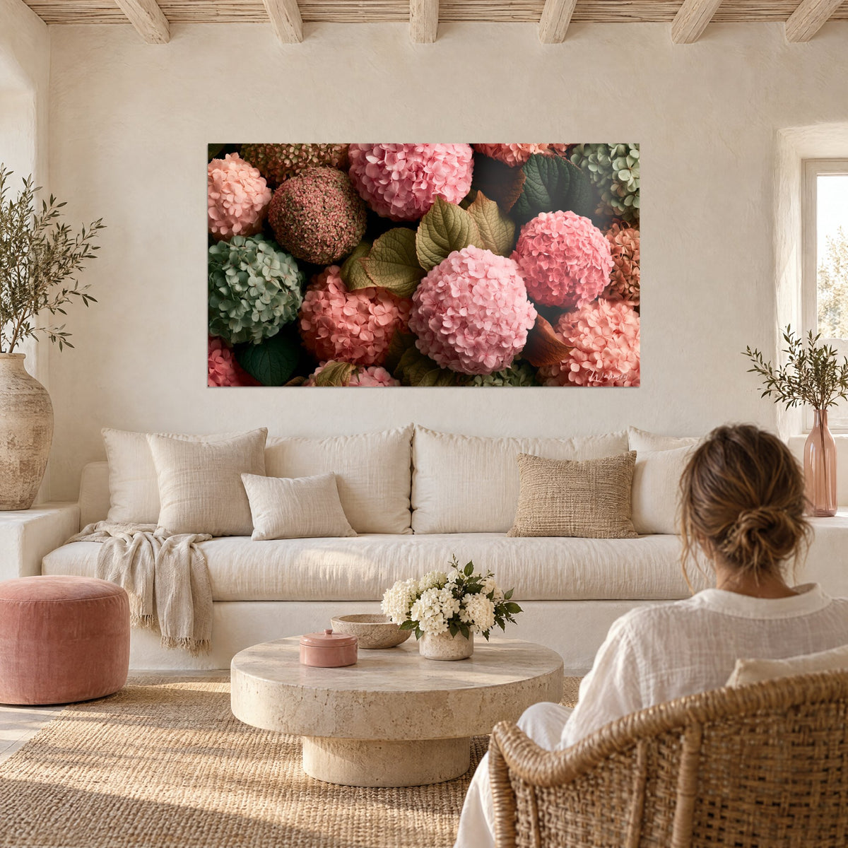 Wall art with a dense bouquet of powder-pink and sage-green hydrangeas, golden leaves, above a sofa in a bright living room