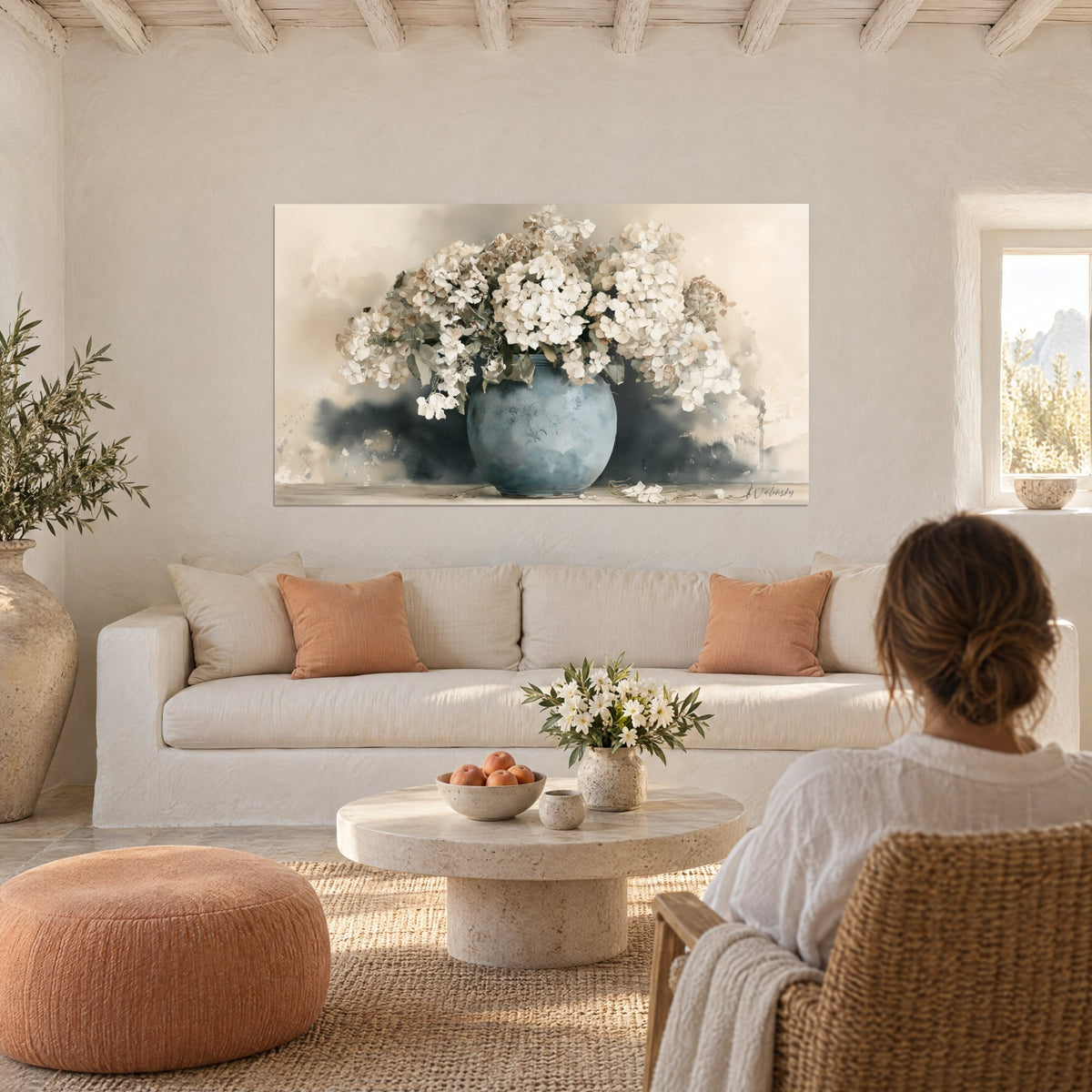 Wall art potbellied blue vase overflowing with white hydrangeas on beige and slate background, above a sofa in a bright living room