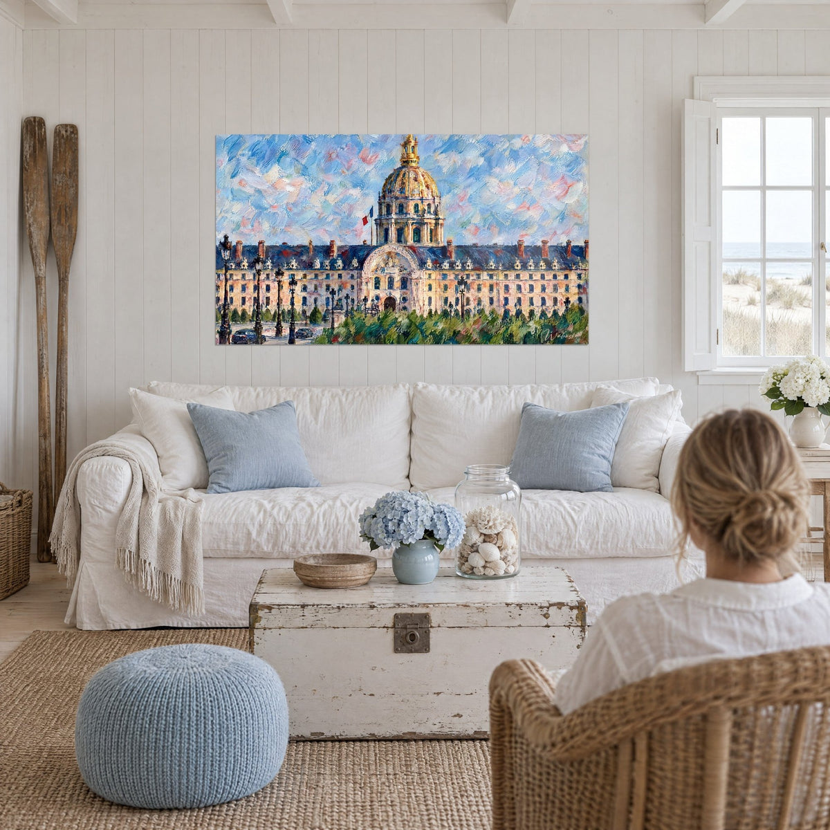 Wall art of the golden dome of Les Invalides in painting, blue and pink sky, ochre facade, above a sofa in a bright living room