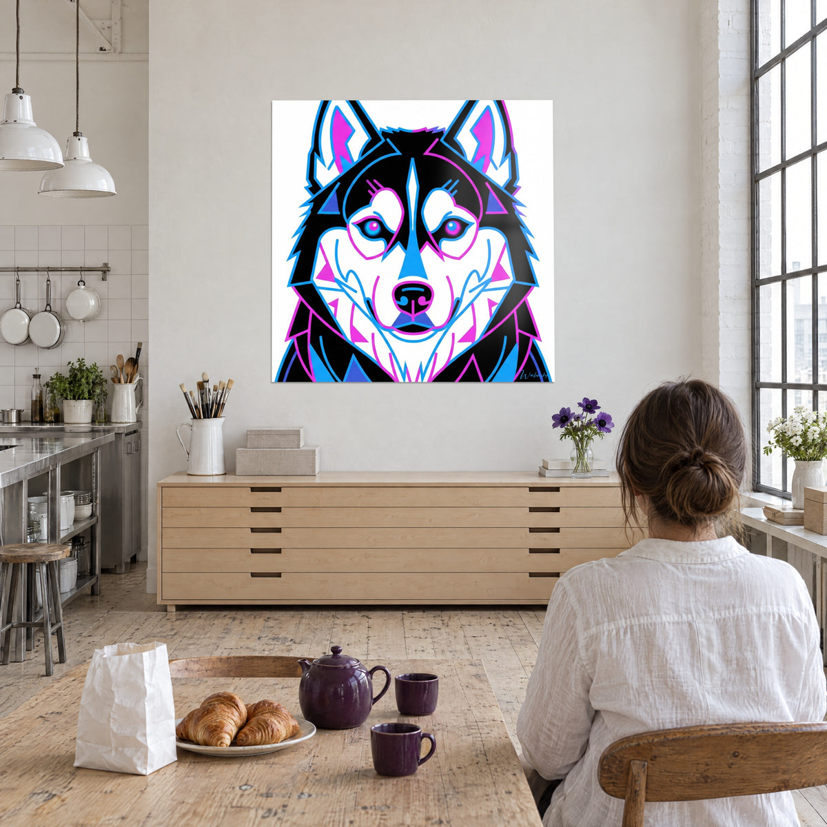 Schilderij Poolwolf met blauwe en magenta irissen, zwarte en witte vlakken, bekeken door een vrouw met haar rug naar de kijker in een kunstenaarsloft