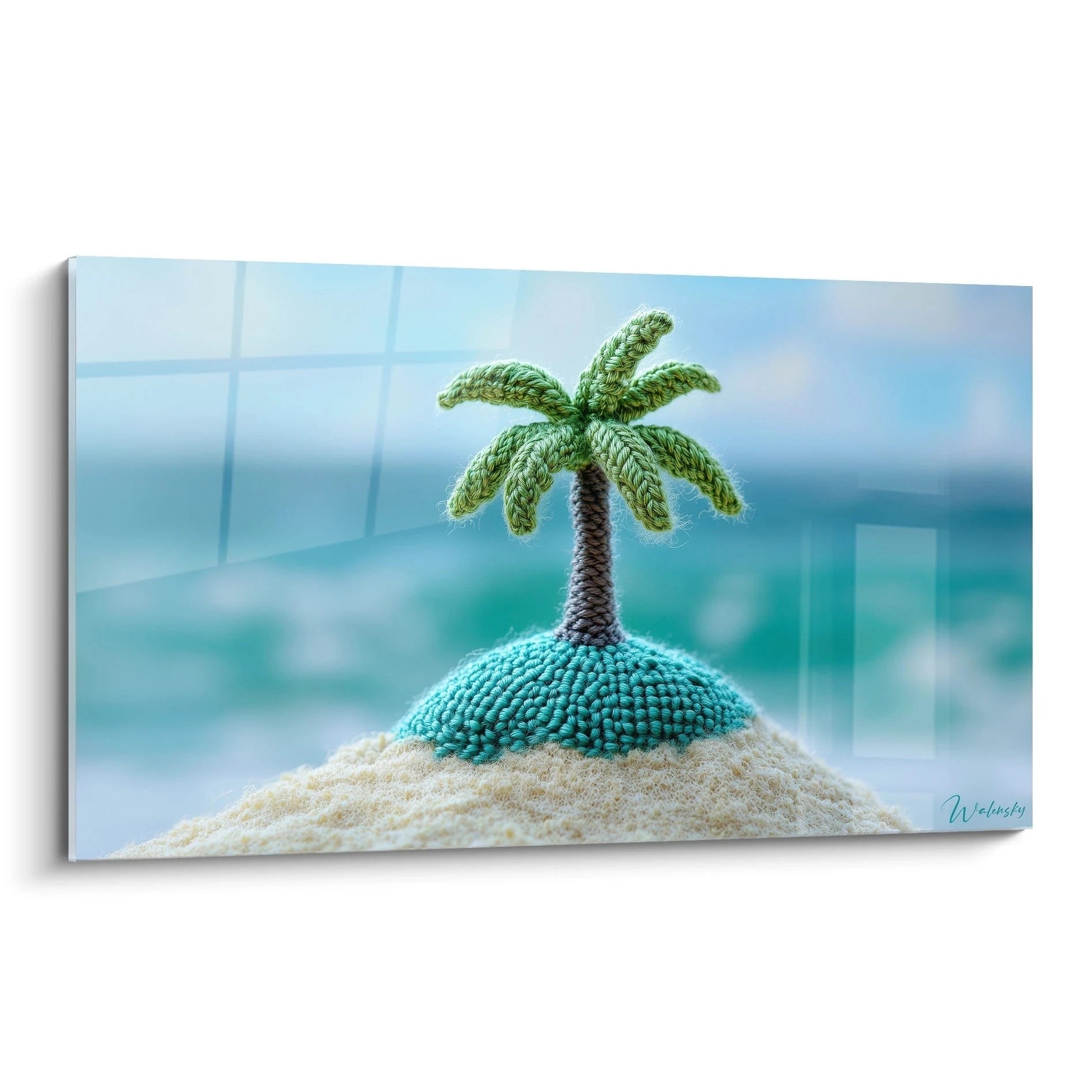Un tableau palmier crocheté représentant un palmier miniature sur une petite île turquoise posée sur du sable beige, avec des textures variées de points de crochet et une composition centrée sur fond bleu flou.
