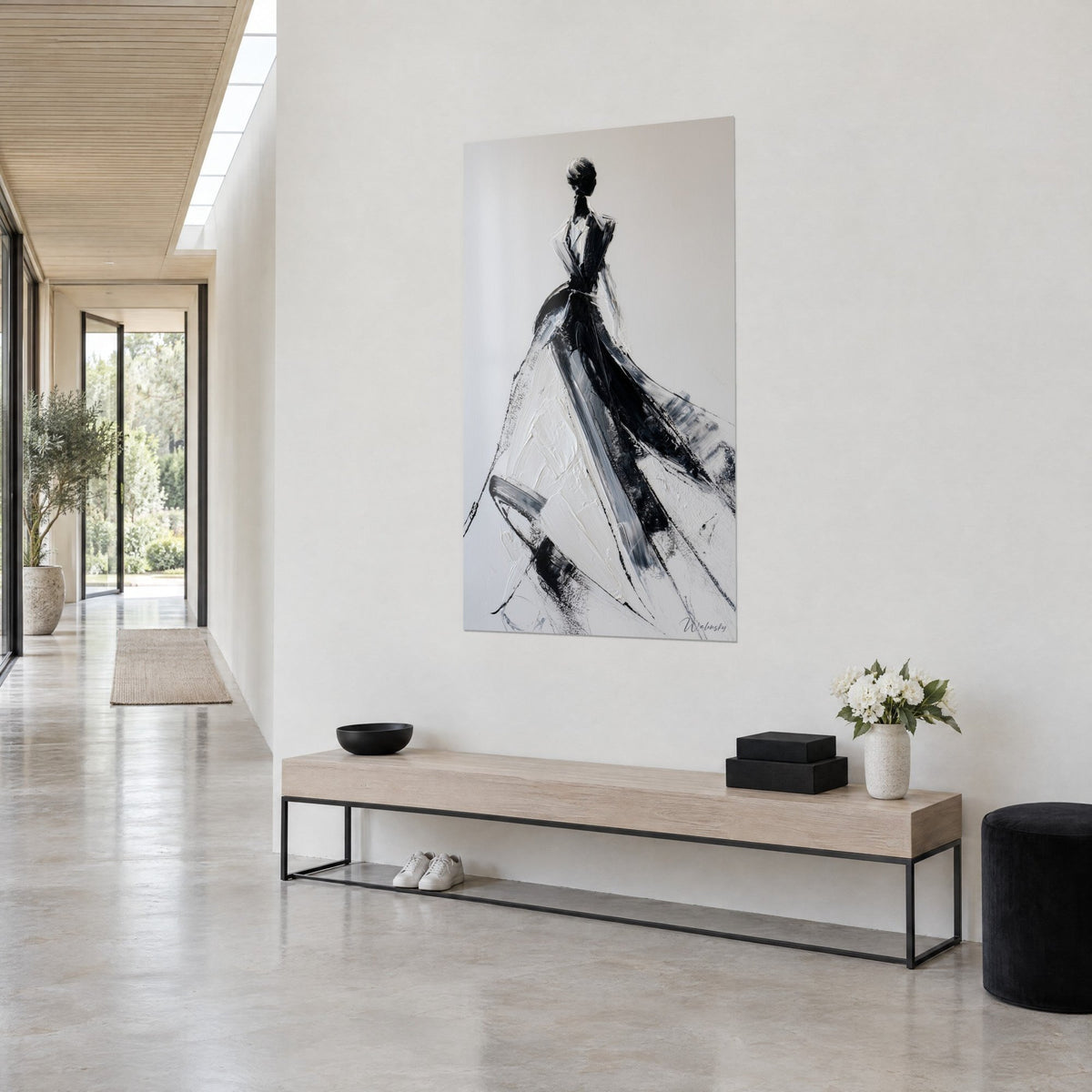 Tableau élégante en gala drapée de traînes noires, jupe ivoire texturée sur fond gris perle, accroché près d'une console en bois, couloir clair