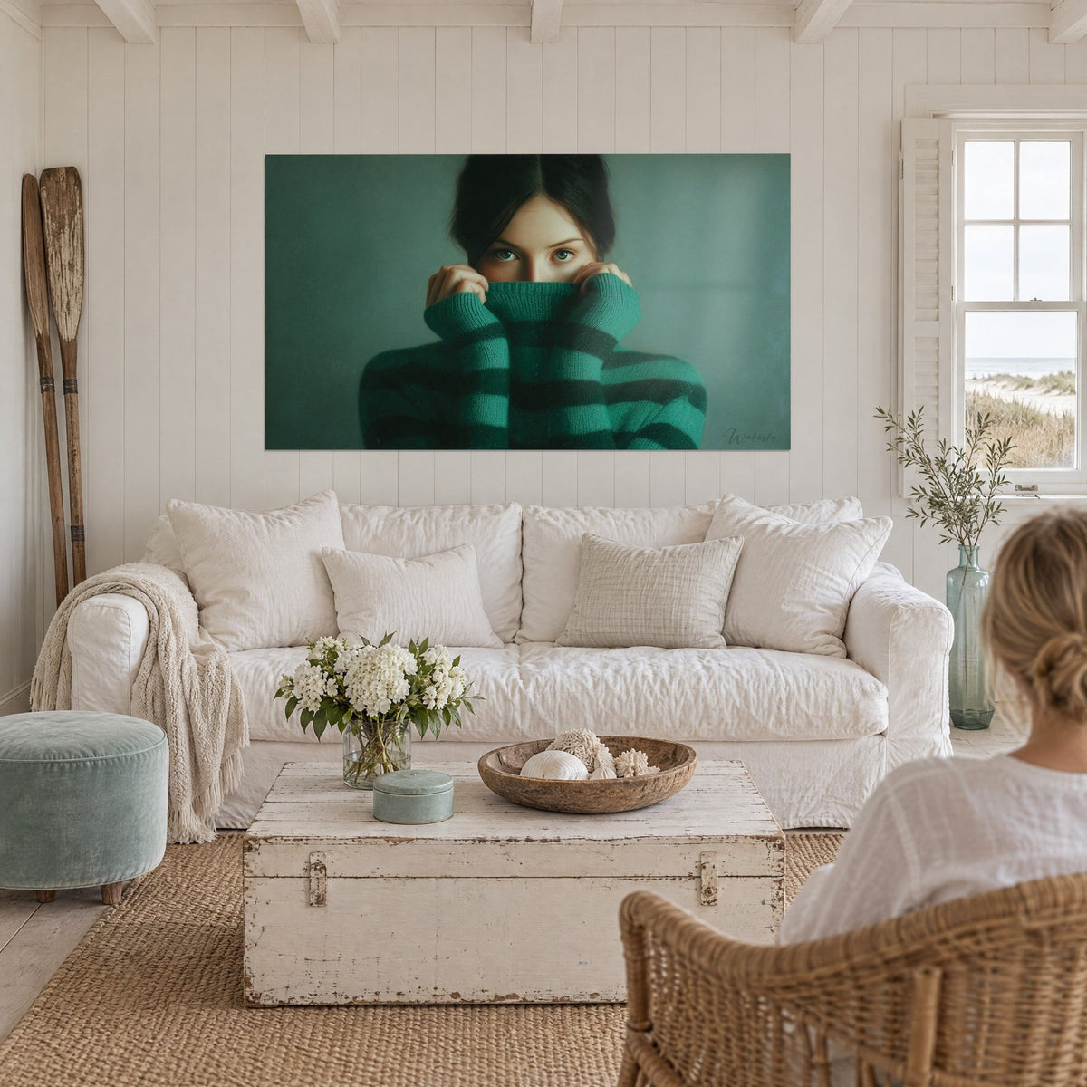 Schilderij jonge vrouw met groene ogen die haar neus verbergt in een gestreepte smaragdgroene coltrui, boven een bank in een lichte woonkamer