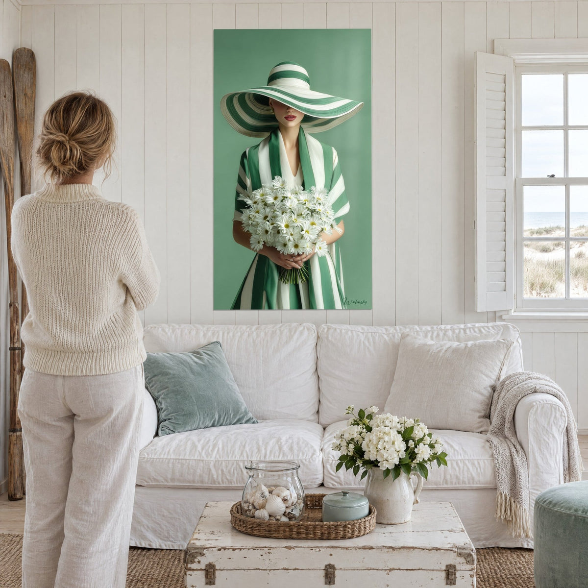 Quadro di un'elegante donna con cappello a righe verdi e bianche che tiene margherite, di spalle, sopra un divano in un soggiorno luminoso