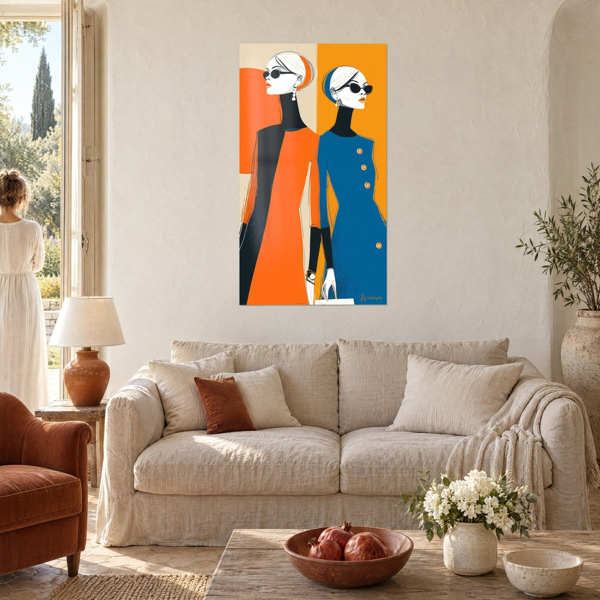 Tableau duo de mannequins stylisées en robes orange et bleu marine, lunettes noires, au-dessus d'un canapé dans un salon lumineux