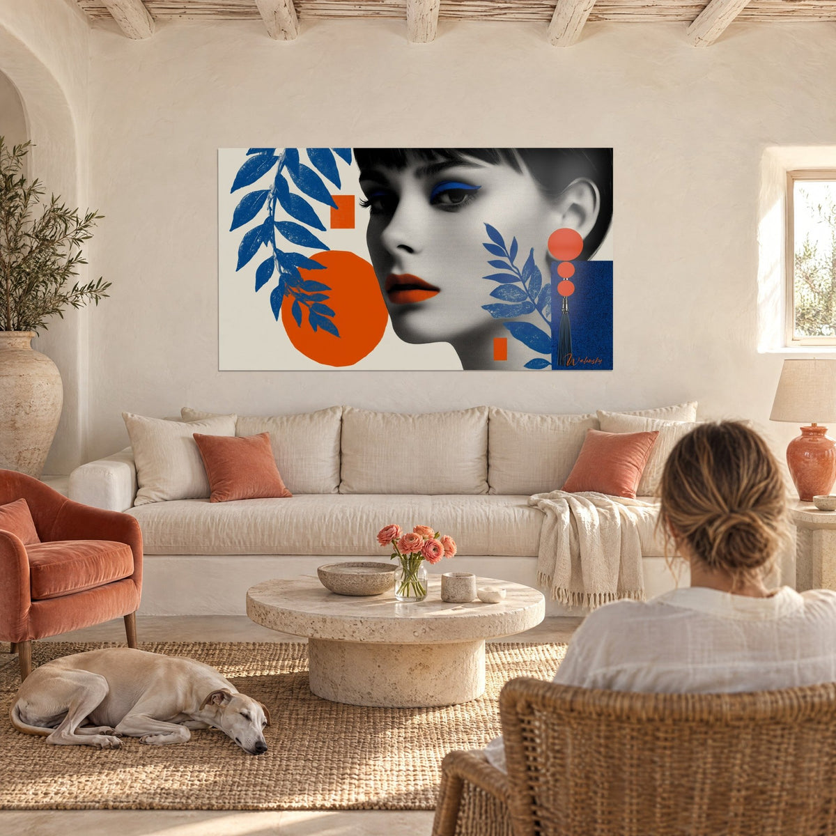 Quadro volto di donna con frangia nera, labbra arancioni, foglie blu cobalto, sopra un divano in un soggiorno luminoso