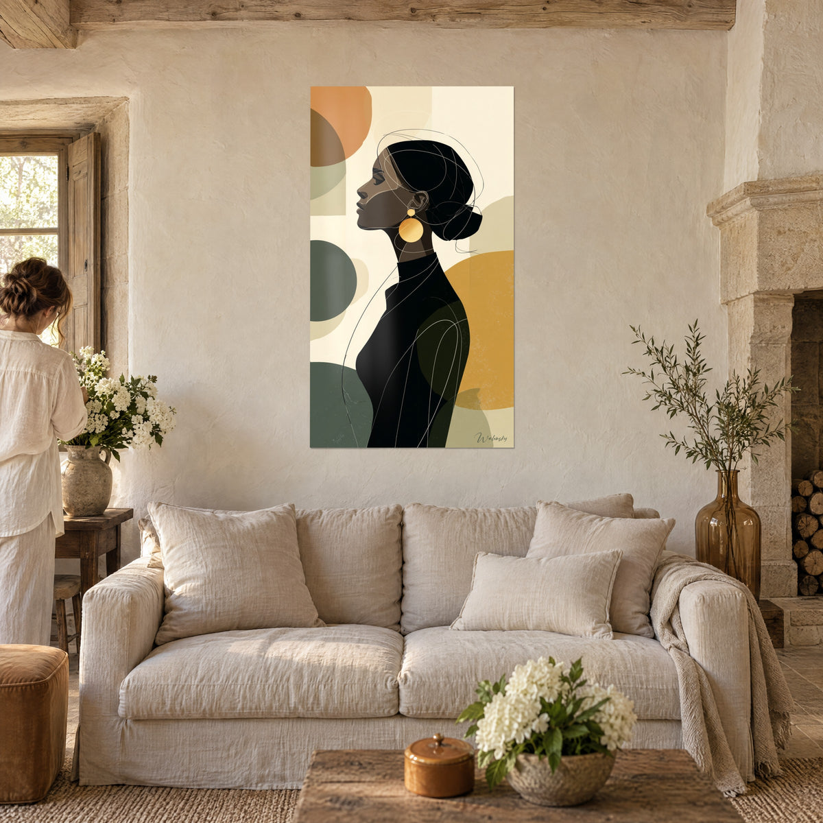 Tableau profil de femme élégante aux grandes boucles dorées, aplats ocre et vert sauge, au-dessus d'un canapé dans un salon lumineux