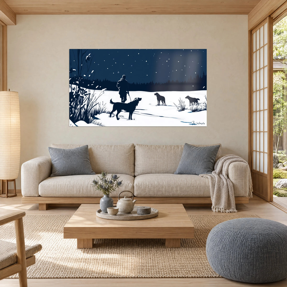 Wall art hunter in navy silhouette leading his dogs across white snow under a starry sky, above a sofa in a bright living room