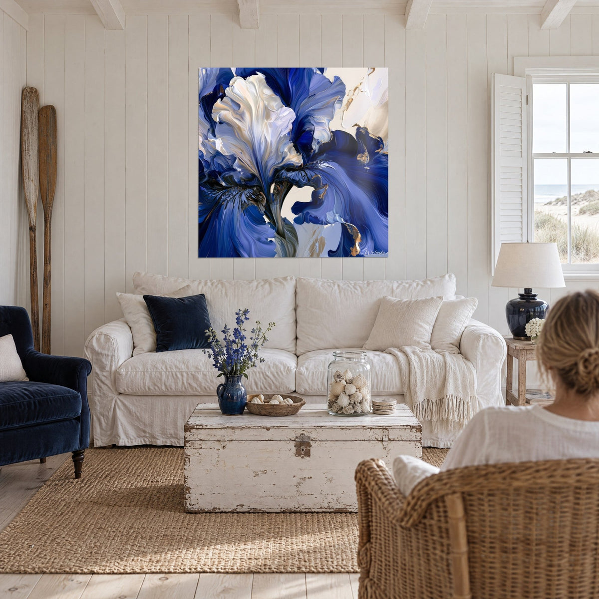 Wall art featuring a giant iris in royal blue and ivory white, swirling petals with golden highlights, above a sofa in a bright living room