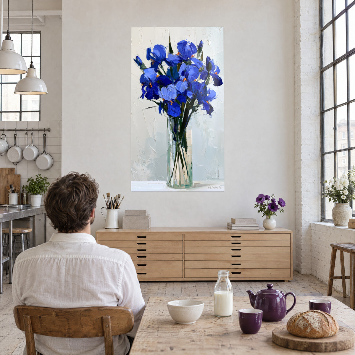 Gemälde Irisstrauß mit Messerspachtel gemalt, Nachtblau und Himmelblau, orangefarbene Staubgefäße, Mann von hinten am Tisch vor einer Kommode aus hellem Holz