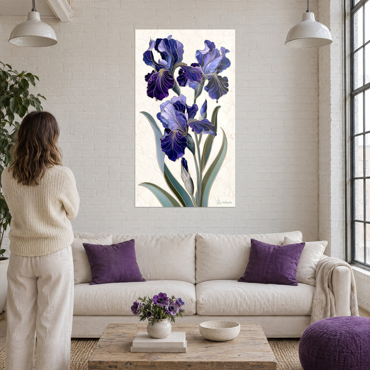 Gemälde Iris in Purpur und Lavendel mit goldenen Rändern auf cremefarbenem Marmorgrund, Frau von hinten, weiße Ziegelwände, über einem Sofa in einem hellen Wohnzimmer