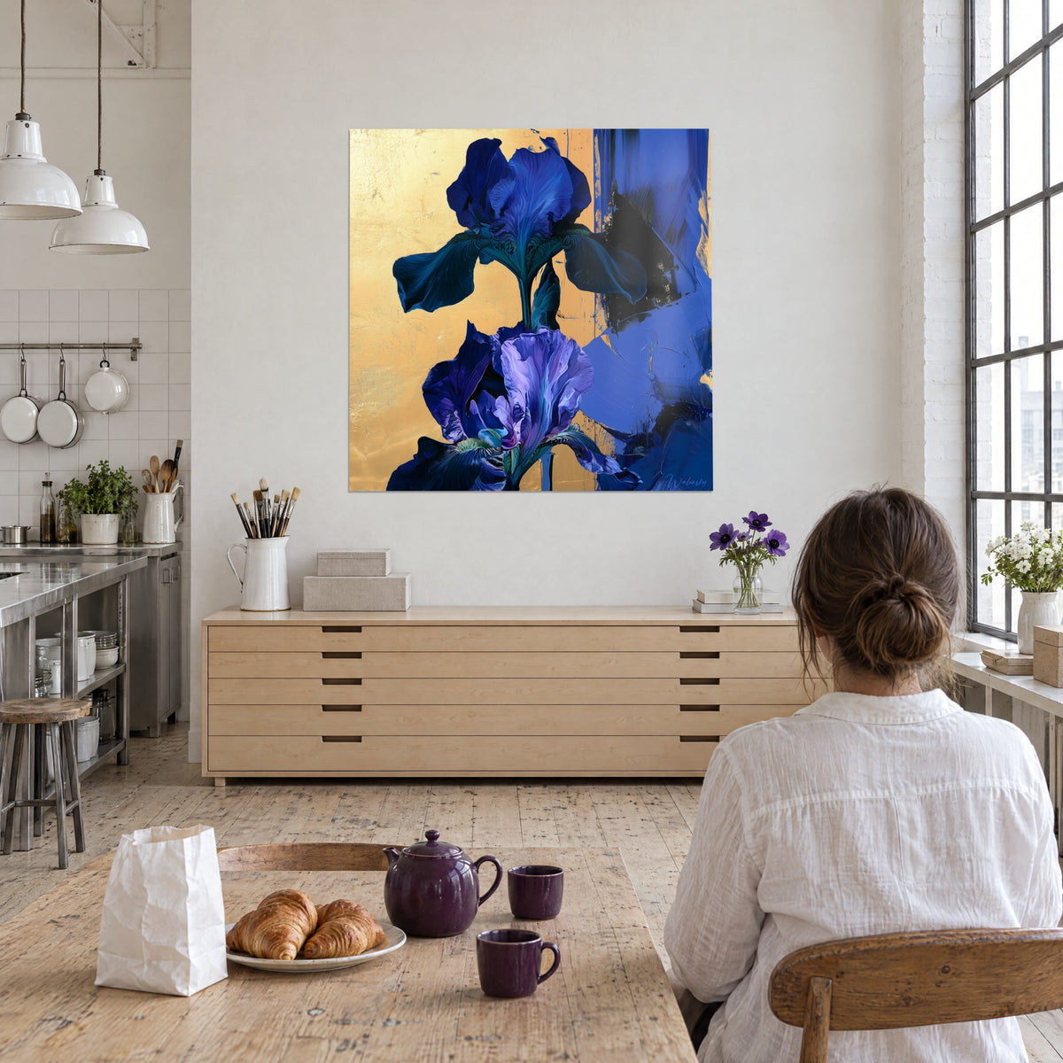 Wall art slender flower stem, lavender and midnight blue irises on matte gold background, viewed from behind by a woman, loft kitchen corner