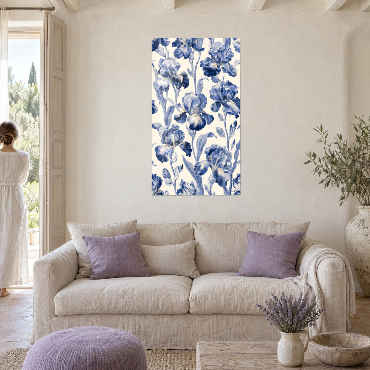 Wall art of indigo and cream bearded irises, ruffled petals, a woman seen from behind gazes over a sofa in a bright living room