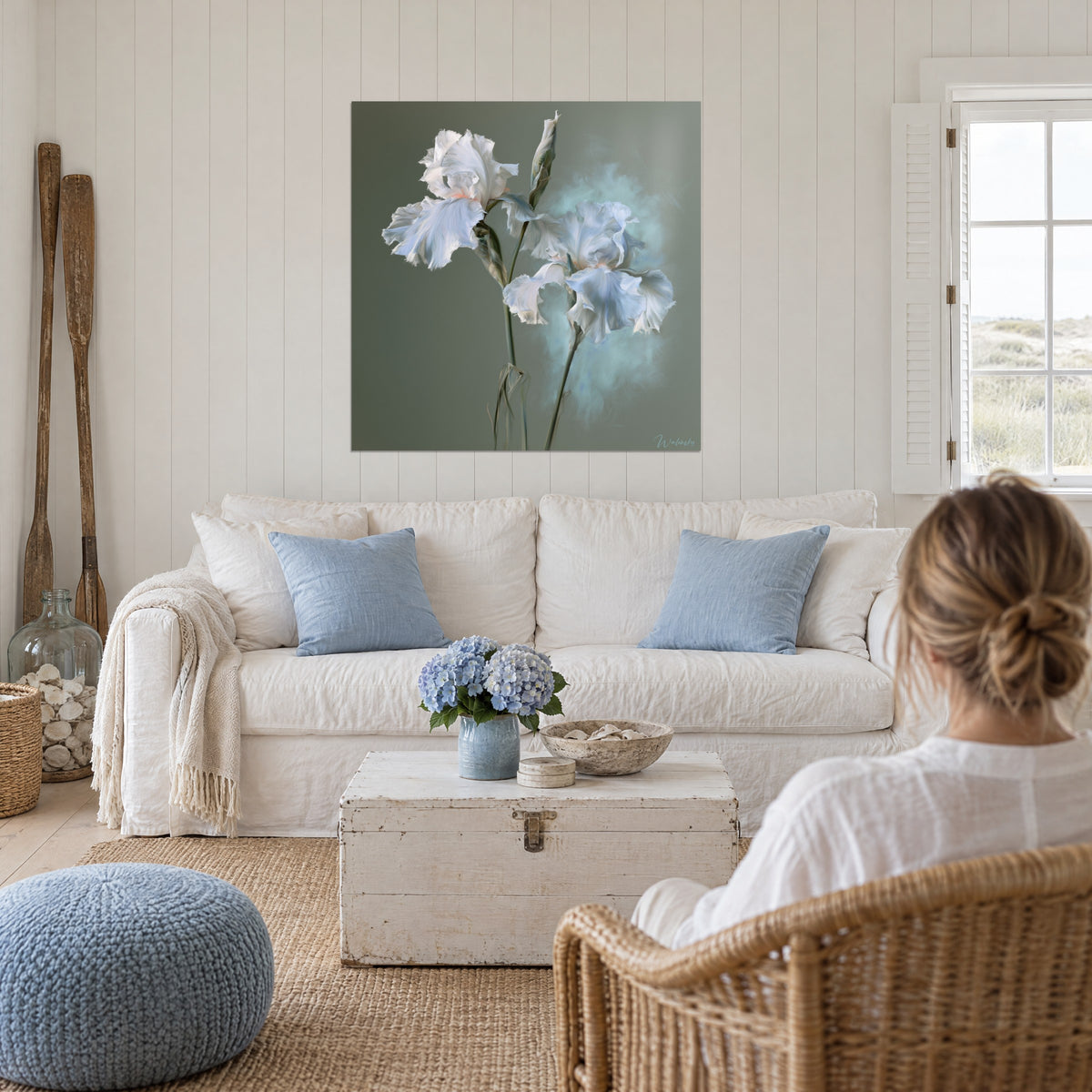 Wall art white irises with crumpled petals, sage green background and a blue glow, above a sofa in a bright living room