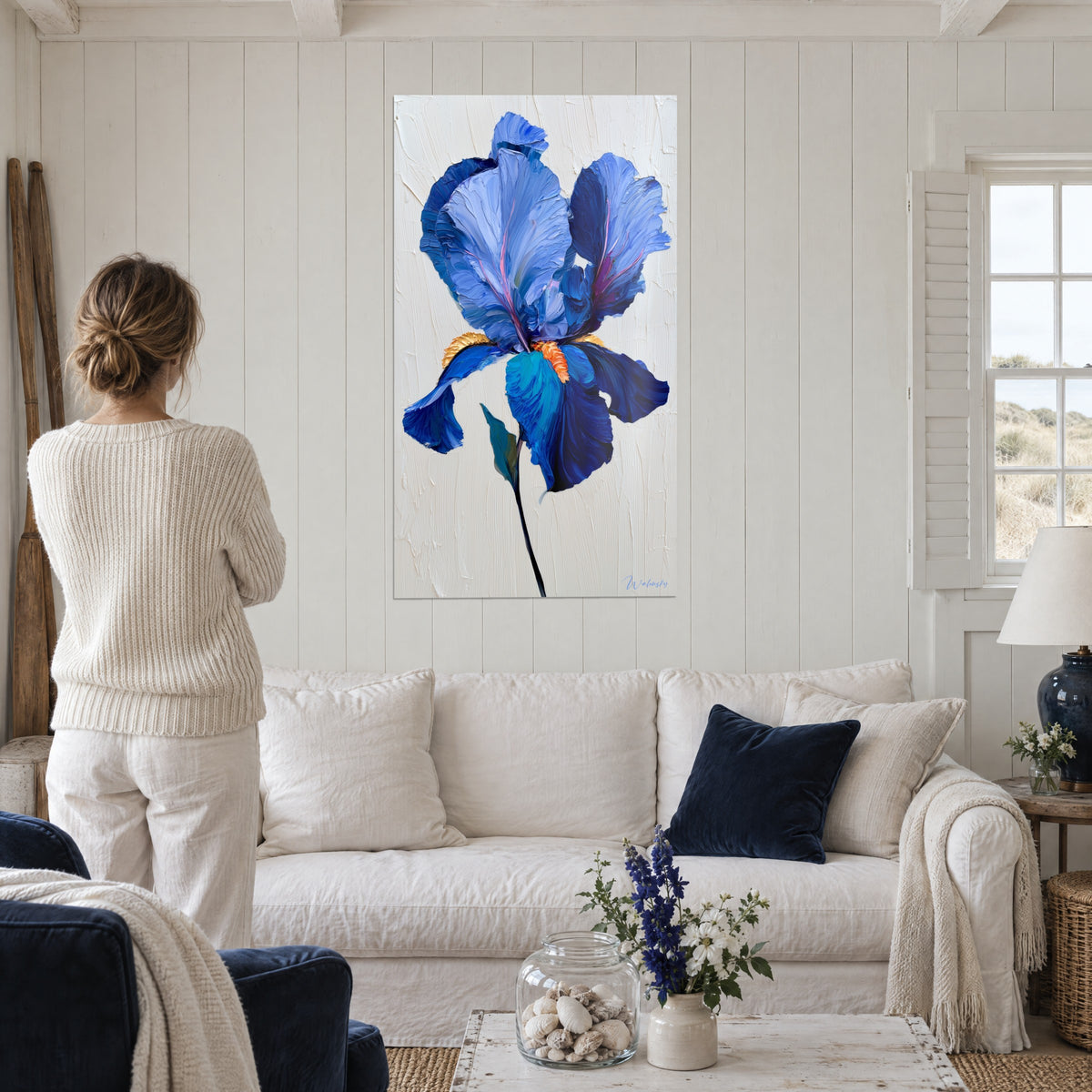 Schilderij met kobaltblauwe iris, dik aangezette bloemblaadjes en oranje baard, boven een bank in een lichte woonkamer