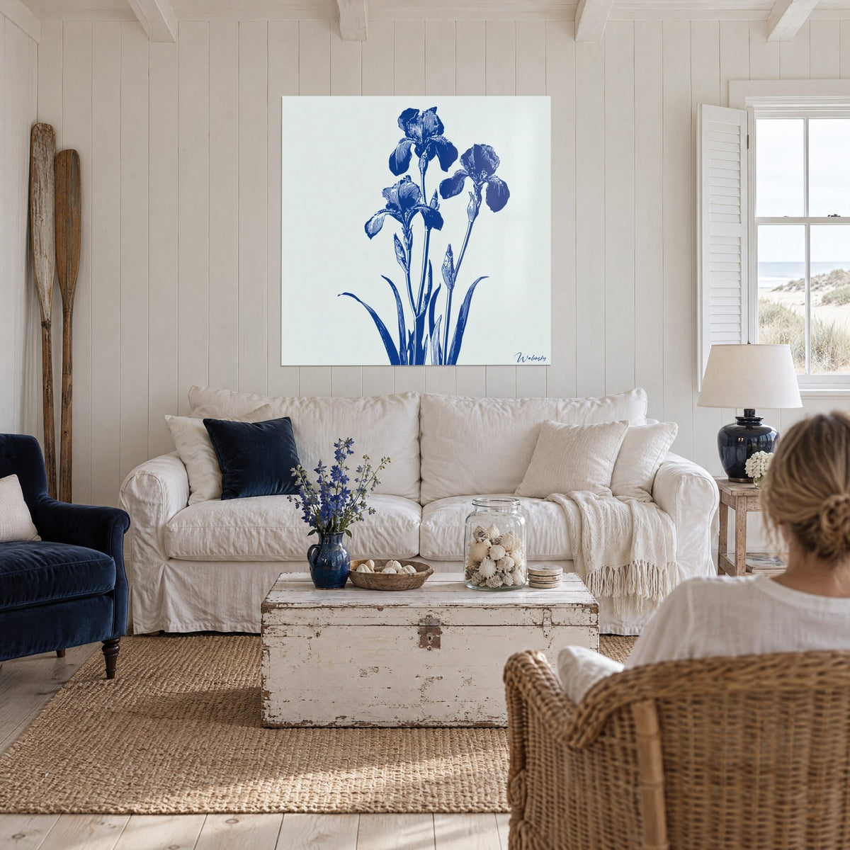 Gemälde drei marineblaue Iris, fein auf gebrochen weißem Grund gestochen, geäderte Blütenblätter, über einem Sofa in einem hellen Wohnzimmer