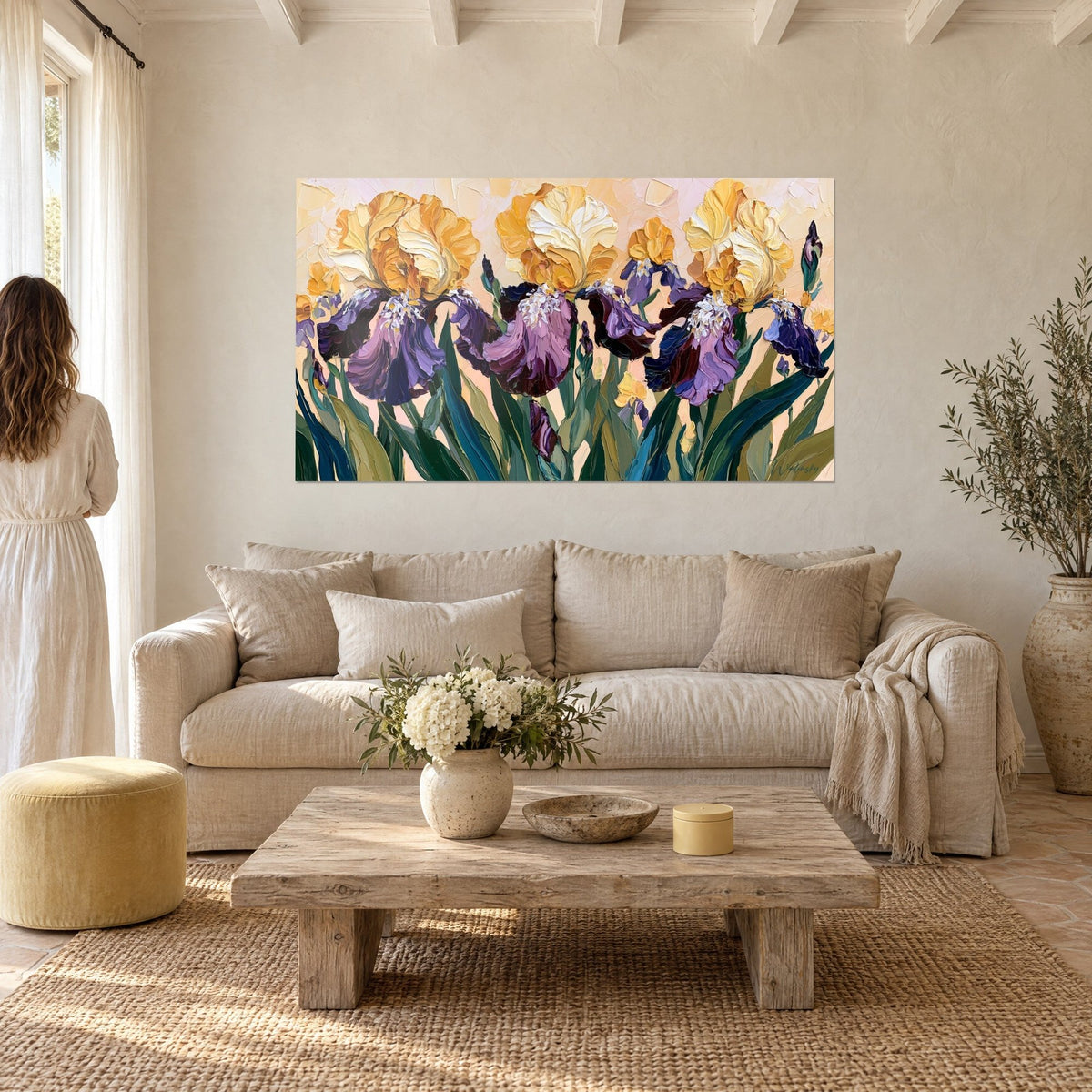 Wall art golden yellow iris with drooping purple petals, fir green leaves, woman seen from behind, above a sofa in a bright living room