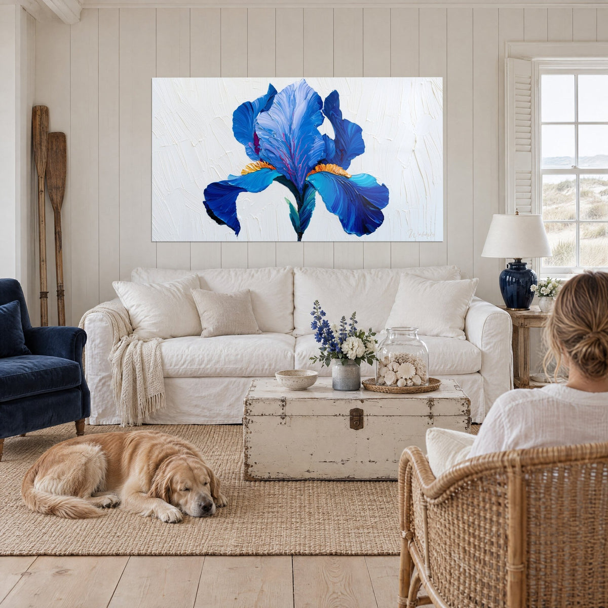 Wall art Cobalt blue iris with an orange heart, thick brushstrokes of petals on a cream background, woman seen from behind, above a sofa in a bright living room