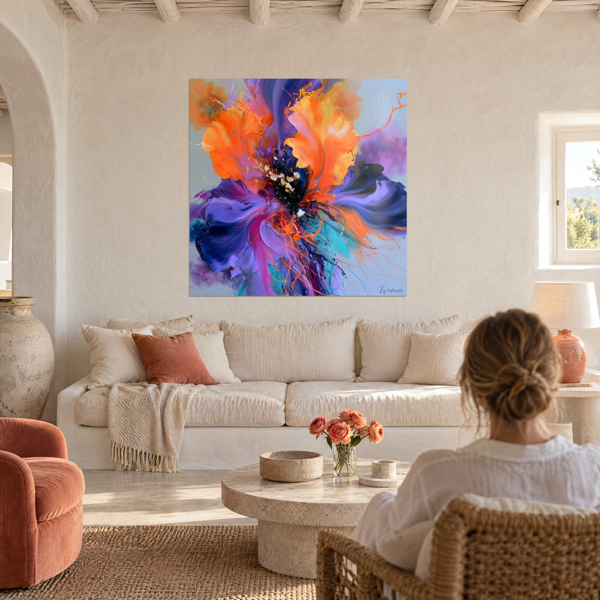 Cuadro flor gigante naranja y violeta de pétalos gruesos, corazón negro moteado de oro, encima de un sofá en un salón luminoso