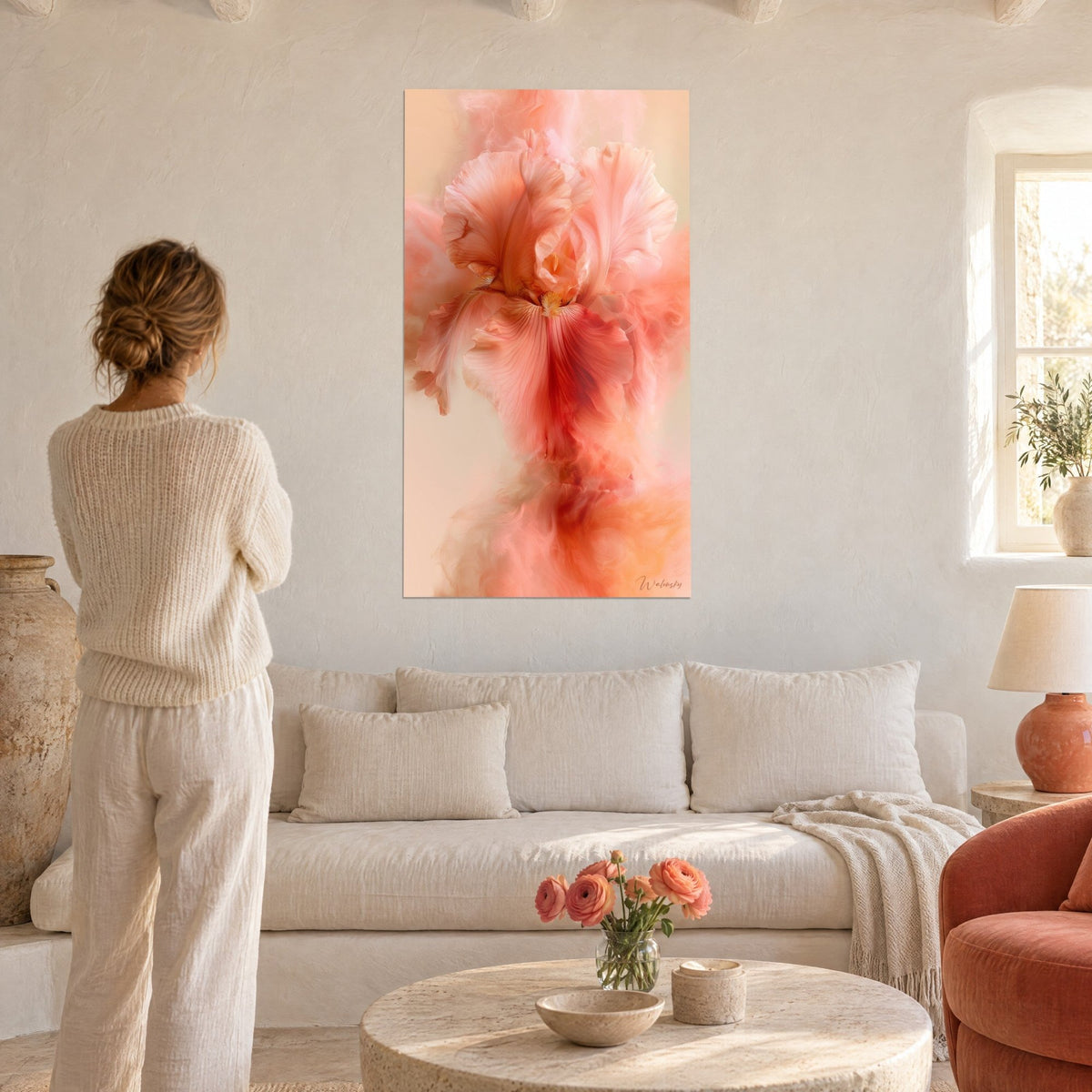 Wall art iris in powdered pink with crumpled petals melting into coral smoke, woman seen from behind, above a sofa in a bright living room