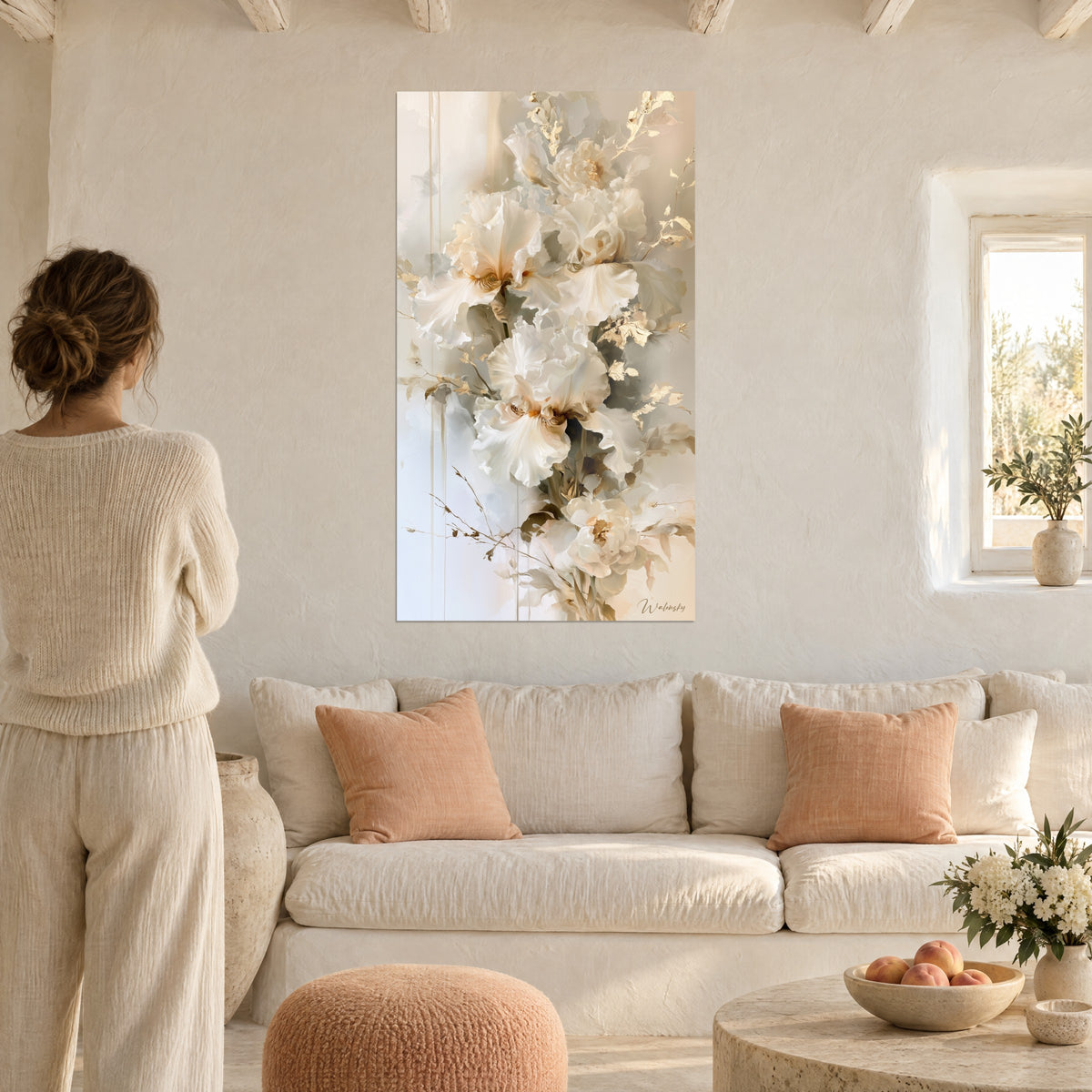 Cuadro iris blancos de pétalos ondulados y toques dorados, mujer de espaldas, sobre un sofá en un salón luminoso