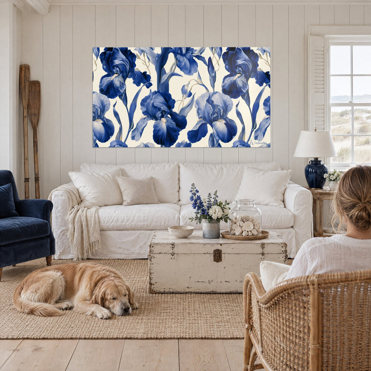 Cuadro de iris azul marino sobre fondo crema, pétalos veteados de blanco, un labrador tumbado delante, encima de un sofá en un salón luminoso