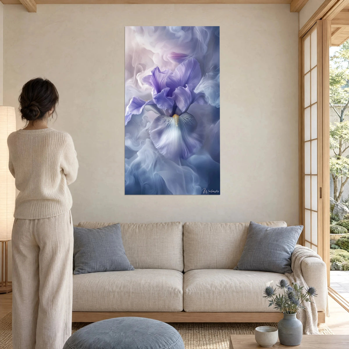 Cuadro iris lavanda con pétalos ondulados en un velo de humo malva y azul, mujer de espaldas, sobre un sofá en un salón luminoso
