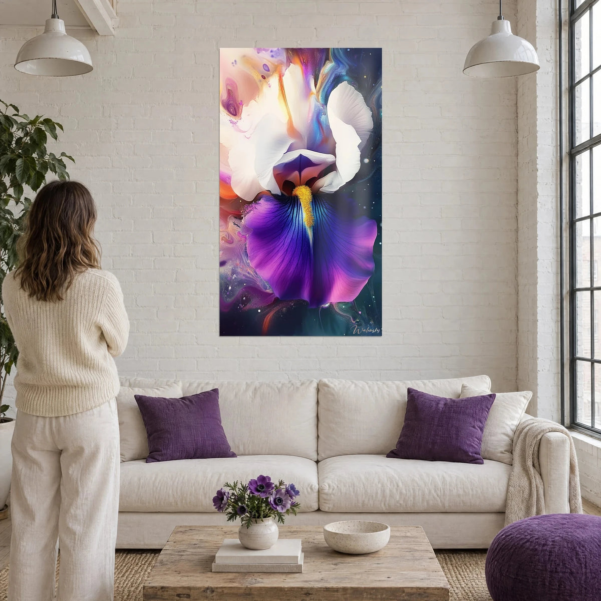 Wall art of a white and violet iris with wavy petals, bright yellow heart, woman seen from behind above a sofa in a bright living room