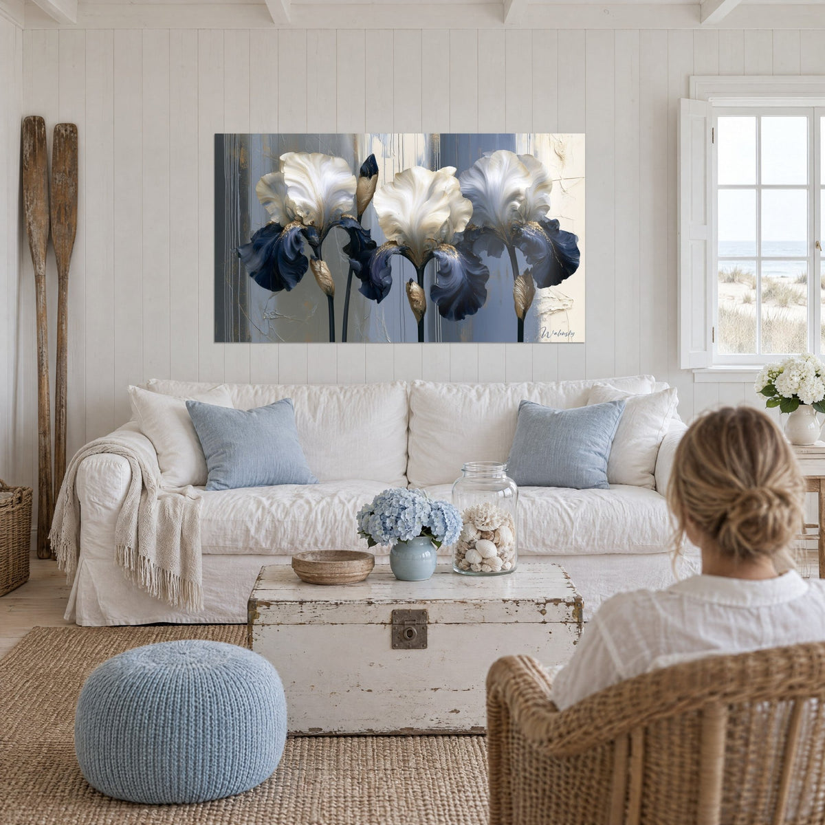 Gemälde weiße Iris mit elfenbeinfarbenen und marineblauen Blütenblättern auf rissigem grauem Grund, über einem Sofa in einem hellen Wohnzimmer