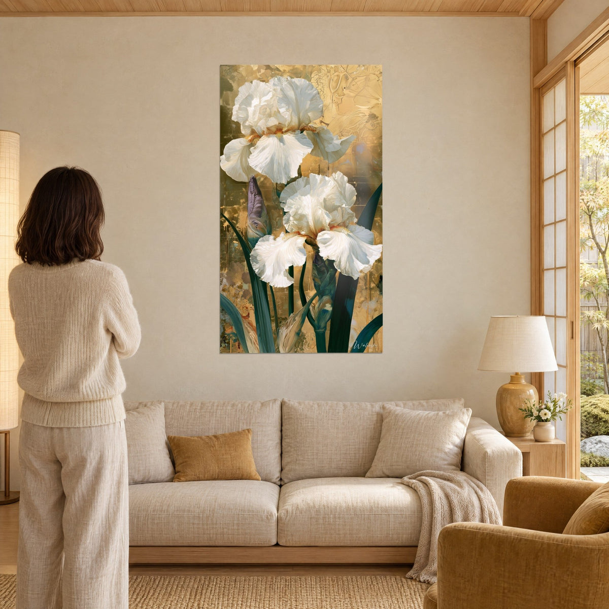 Quadro di iris bianchi con petali arricciati e sgualciti su fondo oro inciso e foglie verde abete, sopra un divano in un soggiorno luminoso