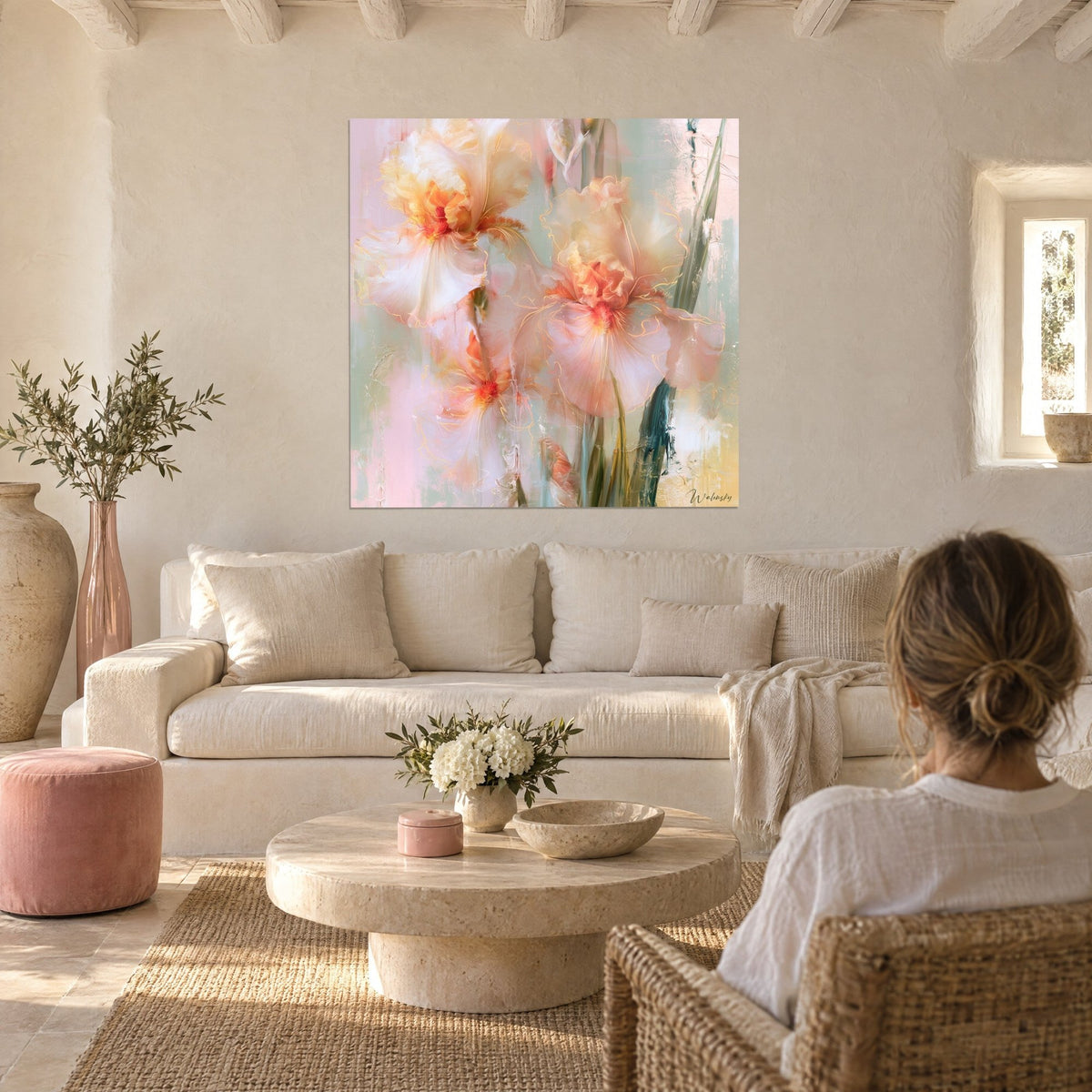 Wall art white irises with gold veining, pale pink petals and orange centers, two people seen from behind above a sofa in a bright living room