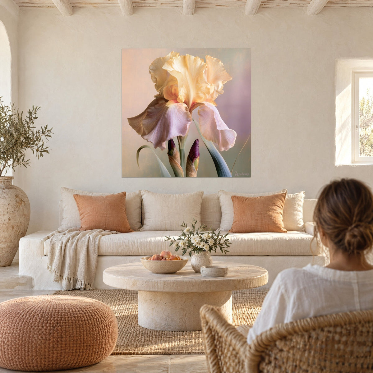 Wall art cream iris with wavy pale pink petals, purple buds, a woman seen from behind above a sofa in a bright living room