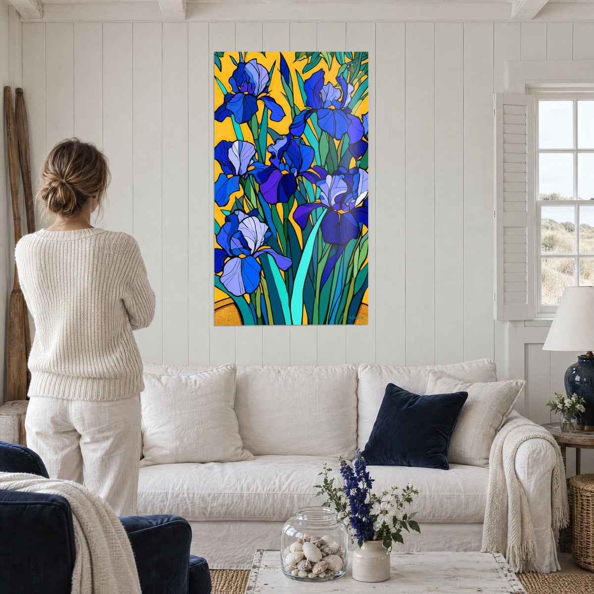 Wall art Cobalt blue irises on saffron yellow background, viewed by a woman seen from behind above a sofa in a bright living room