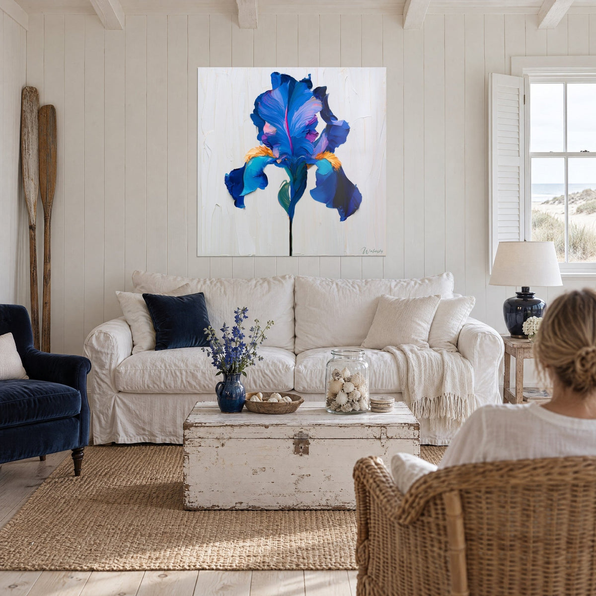 Gemälde mit kobaltblauer Iris, zerknitterte Blütenblätter und orangefarbenes Herz, zwei Personen von hinten vor einem Sofa in einem hellen Wohnzimmer