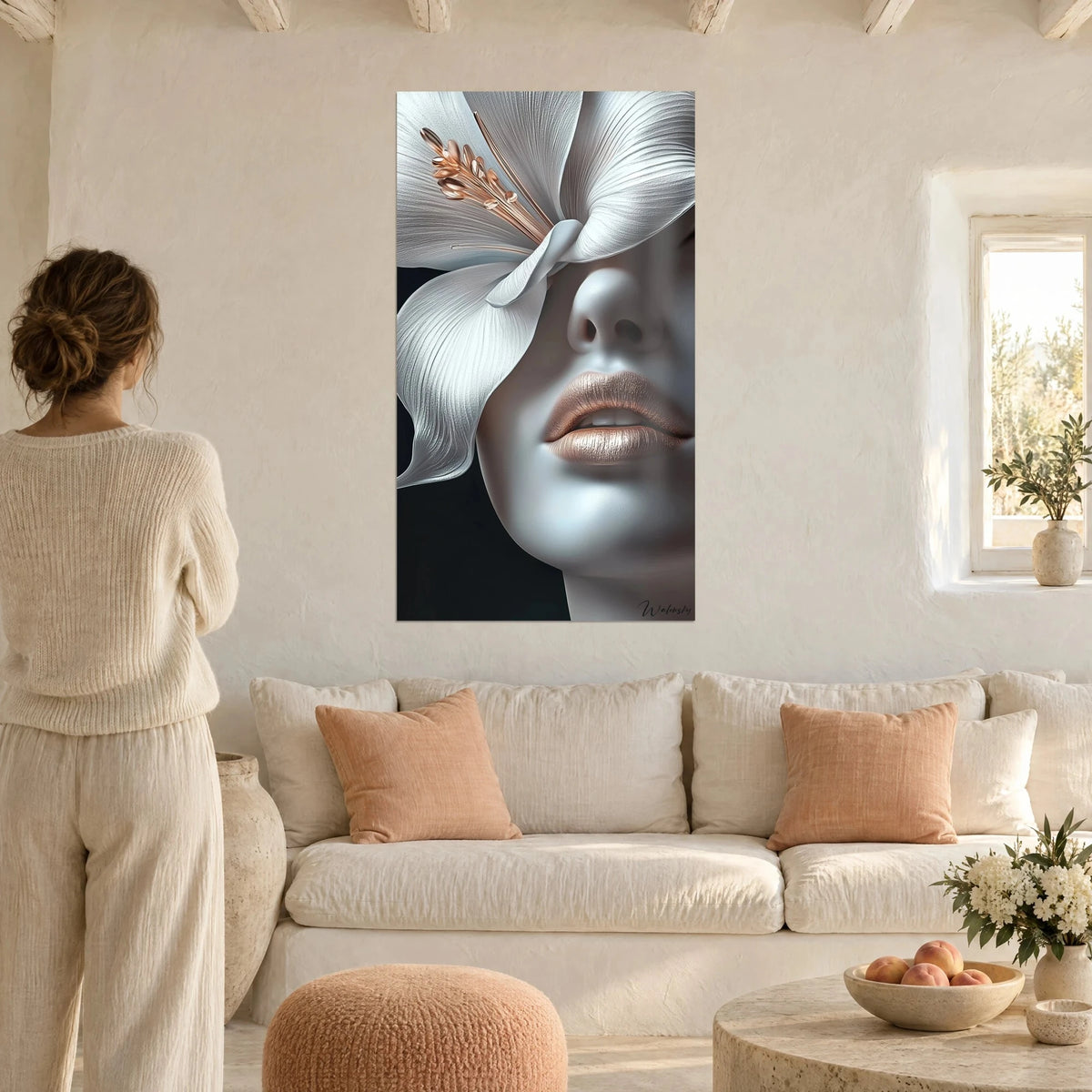 Wall art porcelain face veiled by a white lily with copper stamens, bronze lips, above a sofa in a bright living room