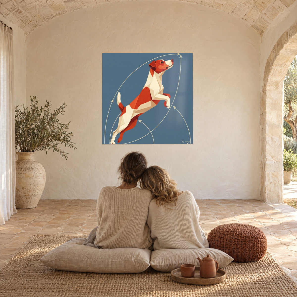 Πίνακας ενός low poly Jack Russell Terrier με επιφάνειες βερμιλιόν και σπασμένου λευκού πάνω σε σκούρο μπλε πλακέ φόντο, μπροστά σε ένα αγκαλιασμένο ζευγάρι σε λινά μαξιλάρια