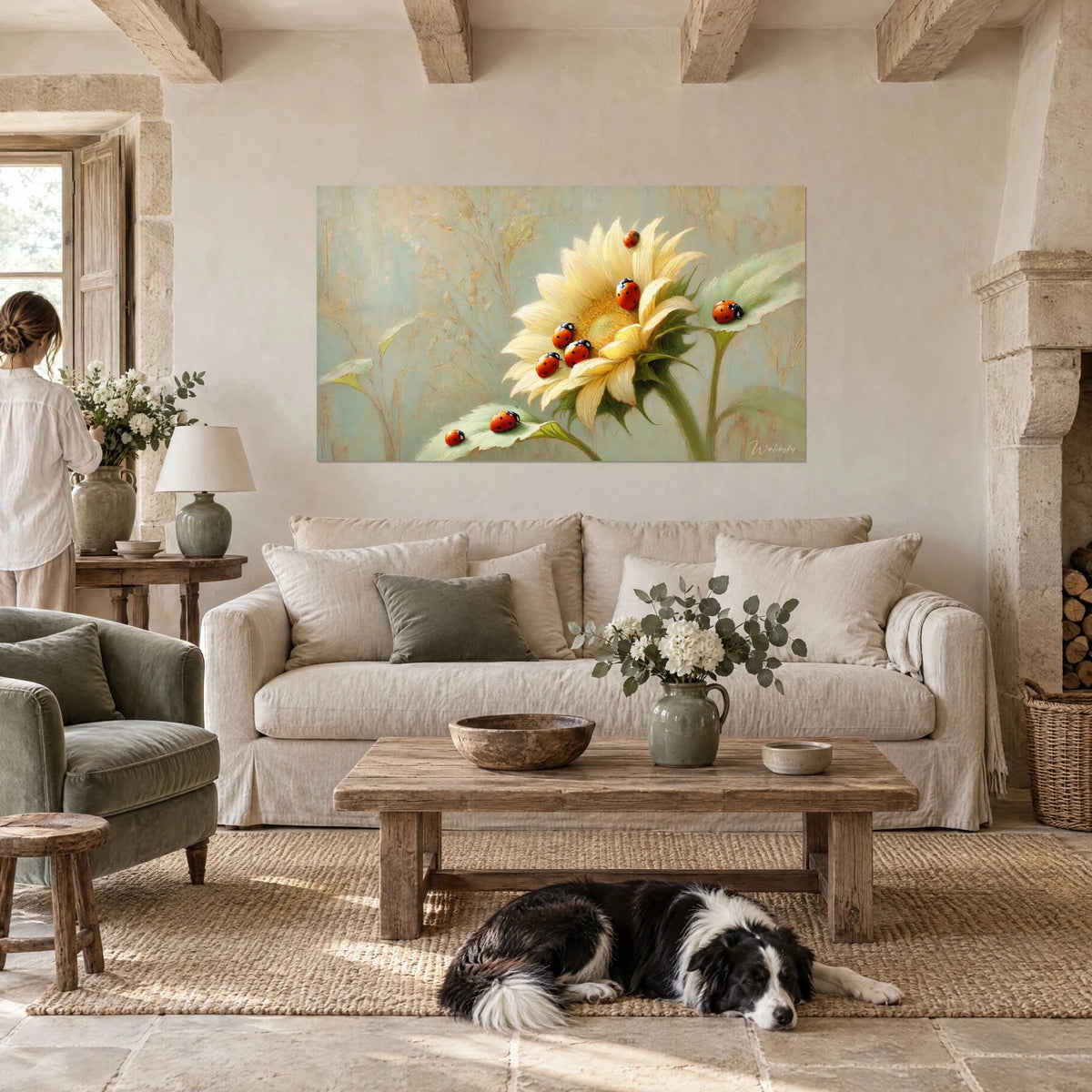 Schilderij met rode lieveheersbeestjes op een crème zonnebloem tegen een blauwgroene achtergrond, een liggende collie eronder, boven een bank in een lichte woonkamer