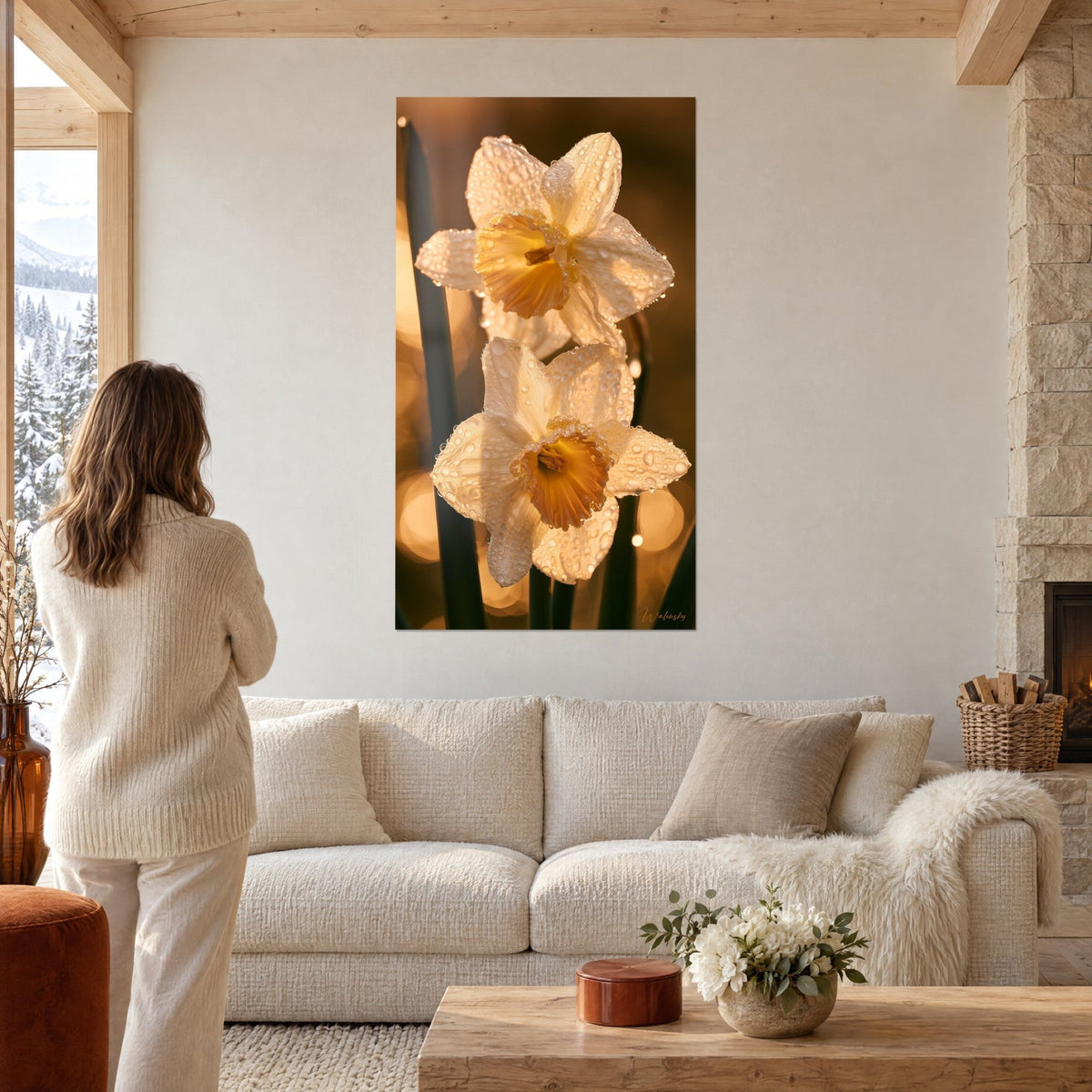 Wall art white daffodils beaded with dew, amber centers, blurred golden background, woman seen from behind above a sofa in a bright living room